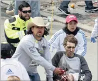  ?? PICTURES: KELVIN MA ?? HORRENDOUS INJURIES: The first responders, including Carlos Arredondo, in the cowboy hat, tend to Jeff Bauman, who lost both his legs in the Boston Marathon bombings. Arredondo is applying tourniquet­s as he runs beside the injured man. Bauman saw one...