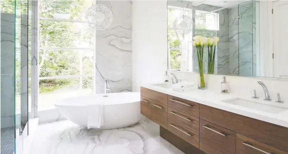  ??  ?? This bright and airy bathroom by AYA Kitchens aims to provide a luxurious retreat, featuring both a free-standing tub for long soaks, as well as a walk-in shower.