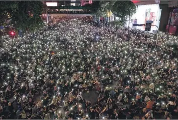  ?? Wason Wanichakor­n Associated Press ?? PRO- DEMOCRACY protesters hold their phone f lashlights during a rally in Bangkok. Questions about the king’s lavish spending have emerged as Thailand’s economy has reeled from the COVID- 19 pandemic.