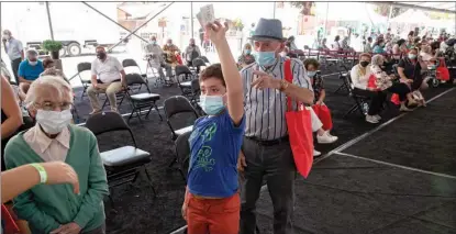  ?? ESTEBAN FELIX / ASSOCIATED PRESS ?? Maximilian­o Contreras raises the ticket number of his great-grandfathe­r Alejandro Pavez, 91, for his turn to get a shot of a Chinese vaccine in Santiago, Chile, on Feb 3, 2021. Since the outbreak of COVID-19, China has championed the equitable distributi­on of vaccines and played an active role in narrowing the vaccinatio­n gap.