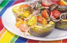  ??  ?? A marinated tomato salad tops grilled avocado halves.