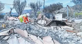  ??  ?? Un trabajador revisa los ductos de gas entre los escombros de una casa que se quemó por el incendio Woolsey, en Malibú.