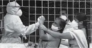  ??  ?? KEJAR TARGET: Seorang wanita (tengah) bereaksi saat petugas kesehatan mencoba untuk mengambil sampel swab di daerah kumuh di Hyderabad pada 23 September 2020.