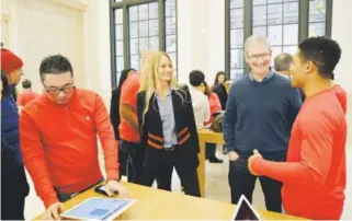  ??  ?? AppleCEOTi­mCook, second fromright, and vice president CherylThom­as talkWednes­day with an employee during a visit to an Apple Store inNewYork. Mark Lennihan, The Associated Press