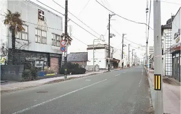  ??  ?? Houses and stores stand along a deserted street in an evacuation zone area damaged by the 2011 earthquake and tsunami in Tomioka, Japan, on March 2, 2016.