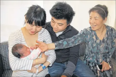  ?? JIM DAY/THE GUARDIAN ?? Shenyan Jiang holds her newborn daughter, Kaixin Wang — the first P.E.I. baby of 2018 born early on New Year’s Day — as her husband, Tengfei Wang, and her mother, Hambing Shen, look on.