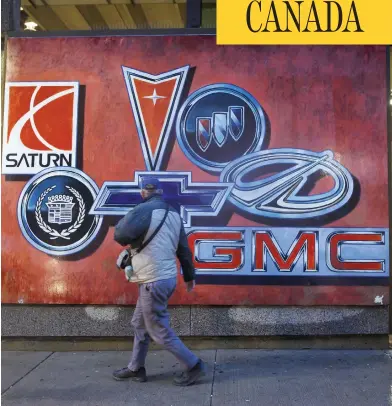  ??  ?? COLE BURSTON/BLOOMBERG A pedestrian walks past a mural depicting vehicle brands in downtown Oshawa. After churning out cars and trucks for more than a century, Oshawa was stunned by the news of General Motors’ planned pullout on Monday.