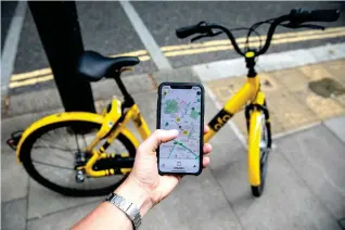  ?? Photo: IC ?? A phone displays the ofo mobile app in front of a shared-bike in London, where ofo launched its bike-sharing service in 2017.