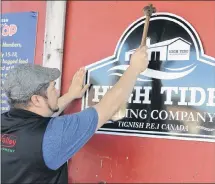  ?? ERIC MCCARTHY/JOURNAL PIONEER ?? Sean McGivern hammers the name of his new enterprise to the front door of a Tignish building where he will soon be hammer milling wheat, barley rye and spelt into flour. He’s leasing a Tignish Co-op building as the starting point for his new business.