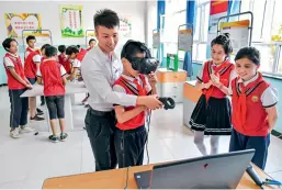  ??  ?? Students experience the VR simulator at the central primary school in Tokkuzak Township, Shufu County, Xinjiang Uygur Autonomous Region.