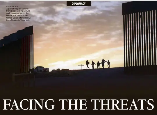  ?? EUGENE GARCIA AP ?? A pair of migrant families from Brazil seeking asylum, walk through a gap in the border wall to reach the United States after crossing from Mexico to Yuma, Ariz.