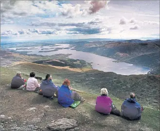  ??  ?? IDYLLIC: Walkers take a rest at the summit of Ben Lomond and enjoy a view of Loch Lomond – where all is not so tranquil as the controvers­y over rights for campers rumbles on. Picture: Colin Mearns