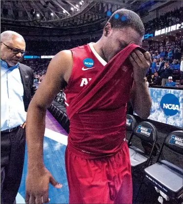  ?? NWA Democrat-Gazette/J.T. WAMPLER ?? Arkansas Razorbacks guard Manny Watkins (right) is followed to the locker room by his father, assistant coach Melvin Watkins, after the team’s 72-65 loss to North Carolina in the South Regional on Sunday at Bon Secours Wellness Arena in Greenville,...