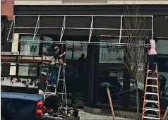  ?? (Special to the Commercial) ?? Awnings go up on downtown buildings at 322 and 324 Main St. as part of the revitaliza­tion project.