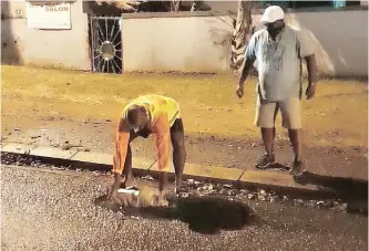  ??  ?? RESIDENTS of Westcliff Drive in Chatsworth fill potholes with sand.