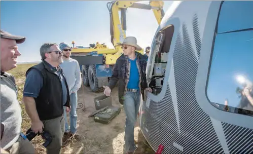  ??  ?? In this undated photo made available by Blue Origin, Jeff Bezos (centre), and others inspect Crew Capsule 2.0 after touchdown in West Texas.