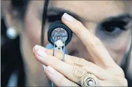  ?? Jack Guez AFP/Getty Images ?? A BUYER checks a diamond at a show in Israel. A new study reveals that ice-VII can form naturally on Earth, thanks to the peculiar properties of diamonds.