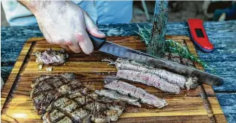  ?? William Luther / Staff photograph­er ?? It’s important to let finished steaks resting off the grill before slicing.