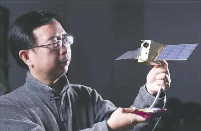  ??  ?? 中国科学技术大学潘建­伟教授在办公室内与“墨子号”量子卫星模型合影
新华社图