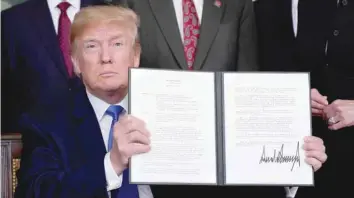  ?? — Reuters ?? US President Donald Trump holds his signed memorandum on IP tariffs on high-tech goods, in Washington.