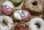  ?? MARK LENNIHAN — THE ASSOCIATED PRESS ?? Pecha Berry Pokeseed doughnuts, top left and center, are displayed in a box of doughnuts from Doughnut Plant in New York. From doughnut shops to zoos, businesses and organizati­ons are finding creative ways to capitalize on “Pokemon Go.”