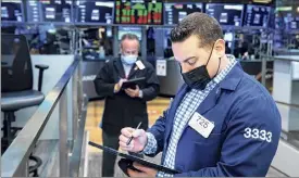  ?? Colin Ziemer / New York Stock Exchange via Associated Press ?? Adam Logan, foreground, works with a fellow trader on the floor Friday. Technology companies helped lift stocks higher on Wall Street.