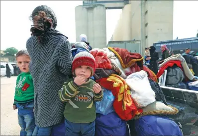  ?? OMAR HAJ KADOUR / AGENCE FRANCE-PRESSE ?? Syrian children stand next to bags as civilians and rebels evacuated from the Eastern Ghouta region arrive in Qalaat al-Madiq, some 45 kilometers northwest of the central city of Hama, on Wednesday.