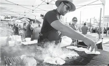  ?? U-T FILE ?? Cesar Toscano cooks on a grill as he and his cousin Claudia Toscano operate their food business, Coal Bros, at the City Heights Street Food Festival in 2019. Festivals and other large gatherings have ceased during the pandemic.