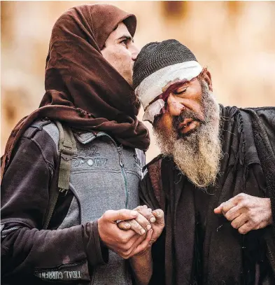  ?? DELIL SOULEIMAN / AFP / GETTY IMAGES ?? An injured man is led out of the village of Baghuz in the eastern Syrian province of Deir Ezzor, the last holdout of the Islamic State, as the U.s.-backed Syrian Democratic Forces (SDF) press their attack.