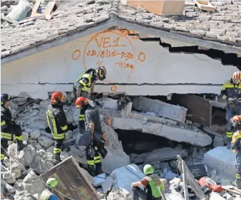  ?? GREGORIO BORGIA, AP ?? Rescuers use paint to signal the time and date of search operations on a building in Pescara del Tronto. Rescue crews raced against time Thursday looking for survivors from the earthquake that leveled three towns in central Italy.