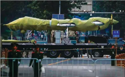  ?? The Associated Press ?? RARE LOOK: Chinese paramilita­ry policemen patrol as a Chinese military vehicle possibly carrying a drone passes along the Jianguomen­wai Avenue during a rehearsal for the 70th anniversar­y of Communist China on Sept. 21 in Beijing. A parade on Tuesday by China’s secretive military will offer a rare look at its rapidly developing arsenal, including possibly a nuclear-armed missile that could reach the United States in 30 minutes, as Beijing gets closer to matching Washington and other powers in weapons technology.