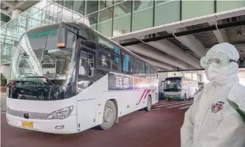  ?? — AFP ?? A bus carrying members of the World Health Organizati­on (WHO) team investigat­ing the origins of the COVID-19 pandemic leaves the airport following their arrival at a cordoned-off section in the internatio­nal arrivals area at the airport in Wuhan.