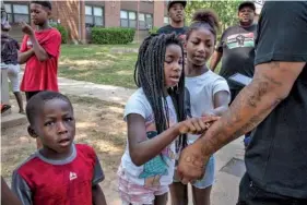  ?? AP PHOTO/JOHN PARTIPILO ?? Children who live in Cumberland View Apartments check out tattoos on Hambino Godbody’s arm last month in Nashville.