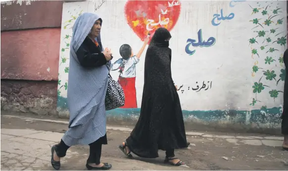  ?? EPA ?? Women pass a mural that reads ‘Peace’ in Afghanista­n’s third-largest city Herat this week. US intelligen­ce agents say women could suffer when US forces leave