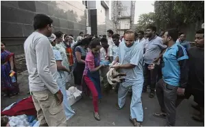  ??  ?? Helping hands: People rushing a victim out of the blazing Kamgar Hospital, which caused eight deaths. — AFP