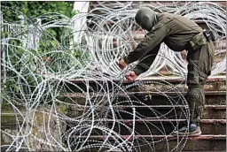  ?? BOJAN SLAVKOVIC / AP ?? KFOR soldiers place a barbed wire in front of the city hall in the town of Zvecan, northern Kosovo on Wednesday. Hundreds of ethnic Serbs began gathering in front of the city hall in their repeated efforts to take over the offices of one of the municipali­ties where ethnic Albanian mayors took up their posts last week.