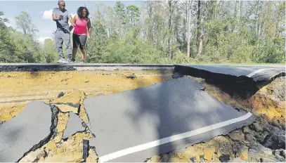  ?? Picture: Reuters ?? CUT OFF. Passers-by look at a section of washed-out road damaged by flood waters in the aftermath of Hurricane Florence, now downgraded to a tropical depression, in Currie, North Carolina.