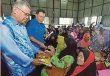  ??  ?? SAPAWI (dua dari kiri) menyampaik­an sumbangan kepada penerima pada Program Mesra Rakyat di Beaufort.