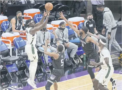  ?? AFP ?? Milwaukee’s Jrue Holiday goes for a three-point shot against Sacramento’s De’Aaron Fox, second left, and Maurice Harkless, second right, during the first half at Golden 1 Center.