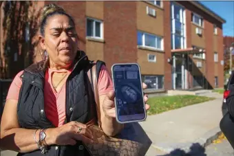  ?? REBA SALDANHA — BOSTON HERALD ?? Yolanda Perez holds a photo of her brother Edwin who was shoot and killed near his Orlando Street home, in background, on Sunday in the city.