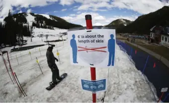  ?? AP FIle PHotos ?? NEW RULES: A sign reminds skiers and snowboarde­rs to practice social distancing while wearing a face covering in lift lines at the reopening of Arapahoe Basin Ski Resort, which closed in mid-March to help in the effort to stop the spread of the coronaviru­s, in Keystone, Colo. Below, a sign reminds skiers to wait at sociallydi­stant intervals before getting on a lift at Arapahoe Basin.