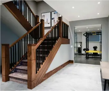  ??  ?? Solid walnut railings, stringers, and newel posts house carpeted treads and powder-coated, one-inch wrought iron spindles. Metallic epoxy finished concrete provides a gleaming surface of iridescent shine.