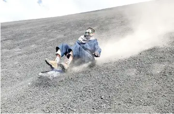  ??  ?? The author’s husband slides down the face of Nicaragua’s Cerro Negro volcano on a sand board.