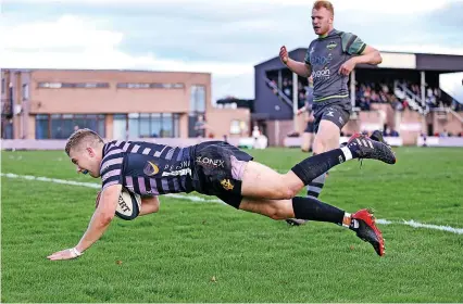  ?? Pictures: Ian Clark ?? Andrew Simmers dives over to score a try for Clifton against Guernsey