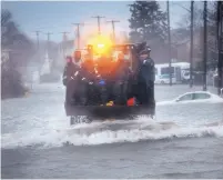  ?? GARY HIGGINS/THE QUINCY PATRIOT LEDGER/ASSOCIATED PRESS ?? The Quincy (Mass.) Marine Unit Dive Team is transporte­d along flooded Sea Street by a front-end loader on Friday. Police rescued people trapped in submerged vehicles.