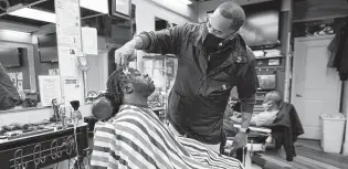  ?? Julio Cortez / Associated Press ?? Mike Brown, right, a barber and health advocate, lines up Vyron Cox Jr.’s facial hair last week in Hyattsvill­e, Md. During the pandemic, Brown has been providing facts to customers about vaccines.