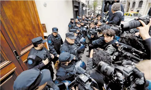  ?? AP ?? Un barrio convulsion­ado. Policías federales ingresan al departamen­to de CFK en Recoleta, rodeados por la prensa, vecinos y militantes K.