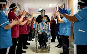  ?? AP ?? Margaret Keenan, 90, is applauded by staff as she returns to her ward after becoming the first patient in Britain to receive the Pfizer-BioNTech Covid-19 vaccine, at University Hospital, Coventry.