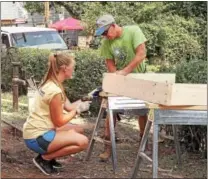  ??  ?? Volunteers cut lumber as the framework for a new sidewalk for the Good Neighbors home repair project.