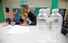  ??  ?? Edward Lucero, of Nambé, submits a sample of his well water Friday with his kids Edward III, 3, and Alek, 1, during the Pojoaque Basin Water Fair at Pojoaque Valley High School.